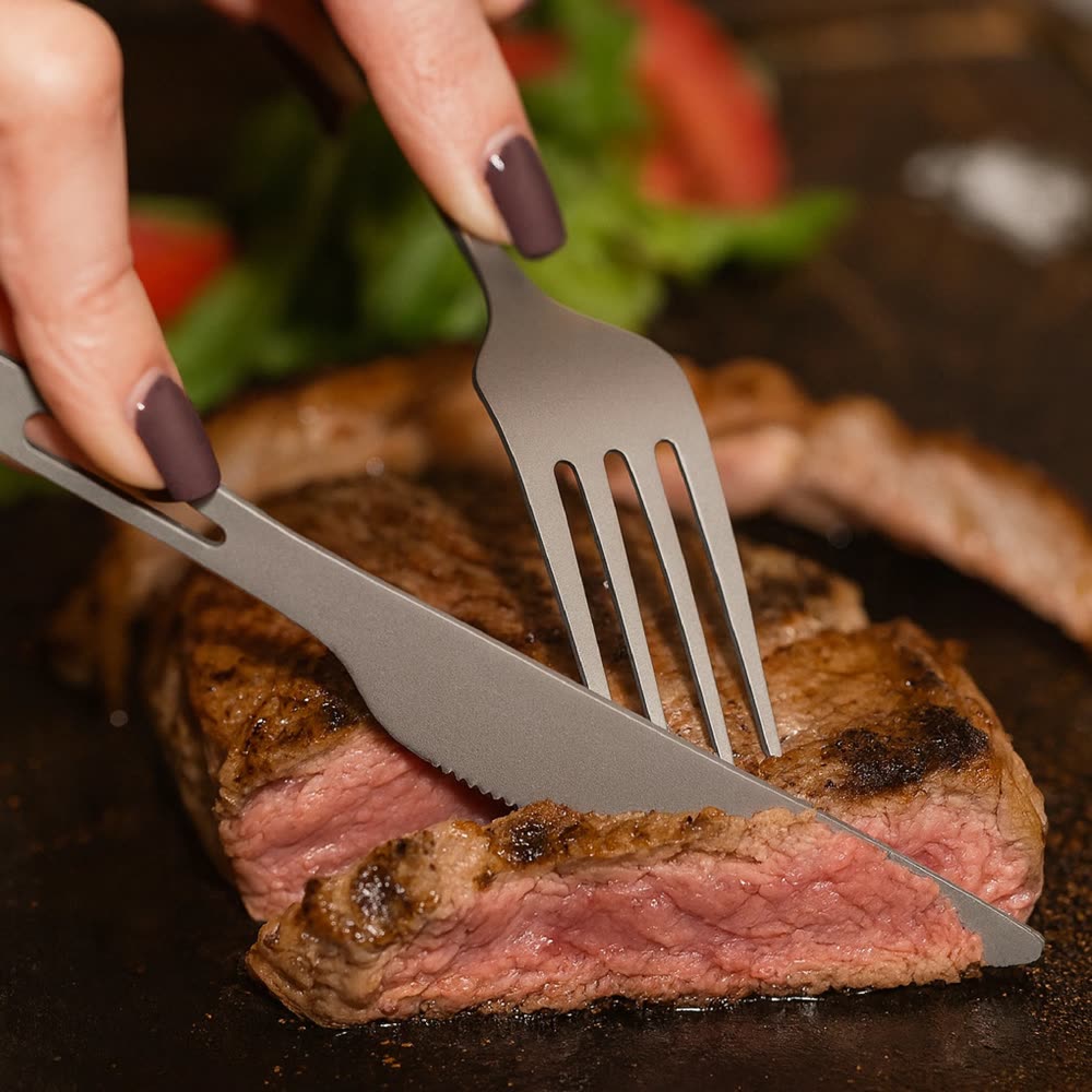 Titanium knife and fork cutting a steak