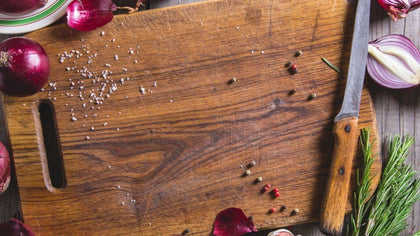 Old wooden cutting board with onions and spices