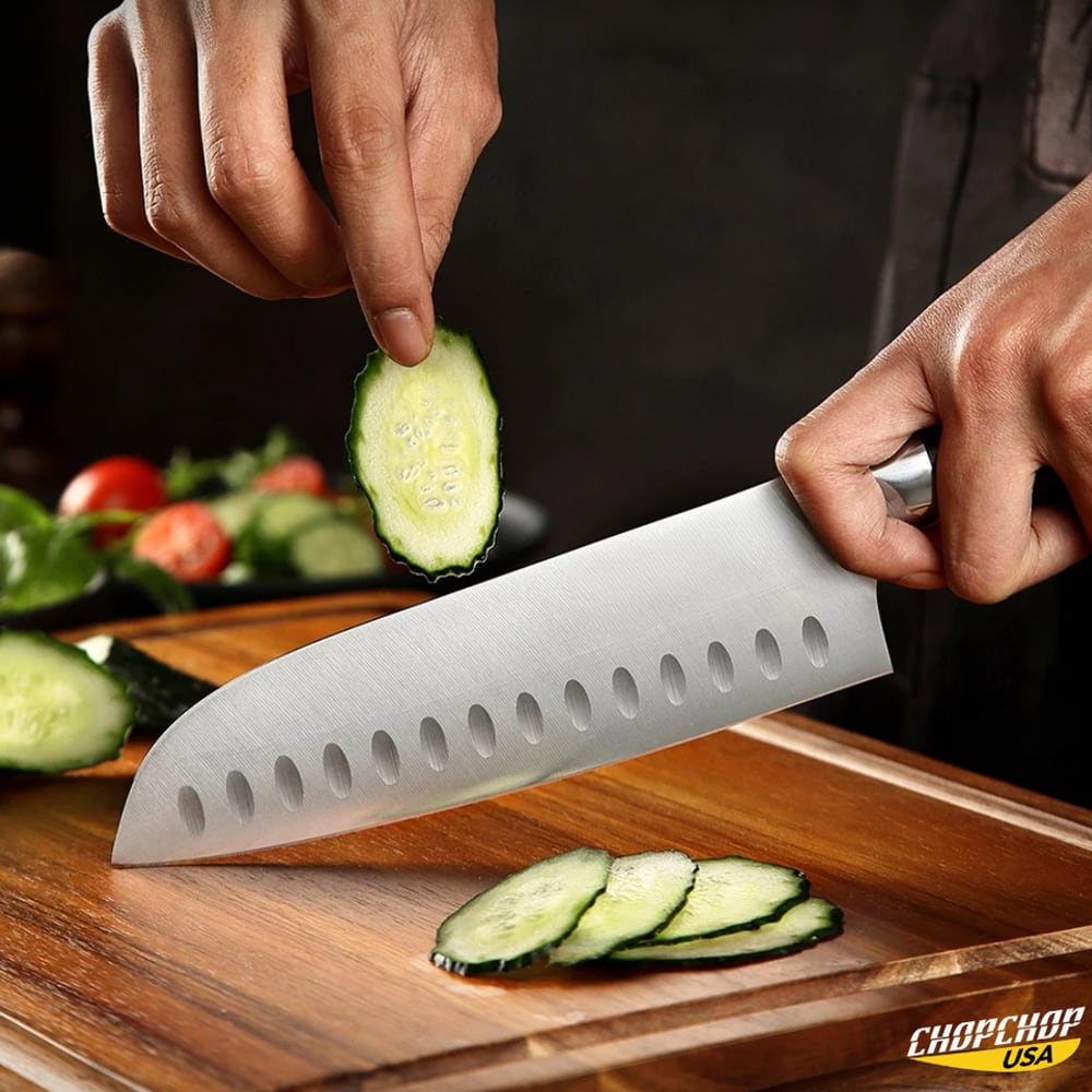 Santoku knife slicing cucumber on a wooden board