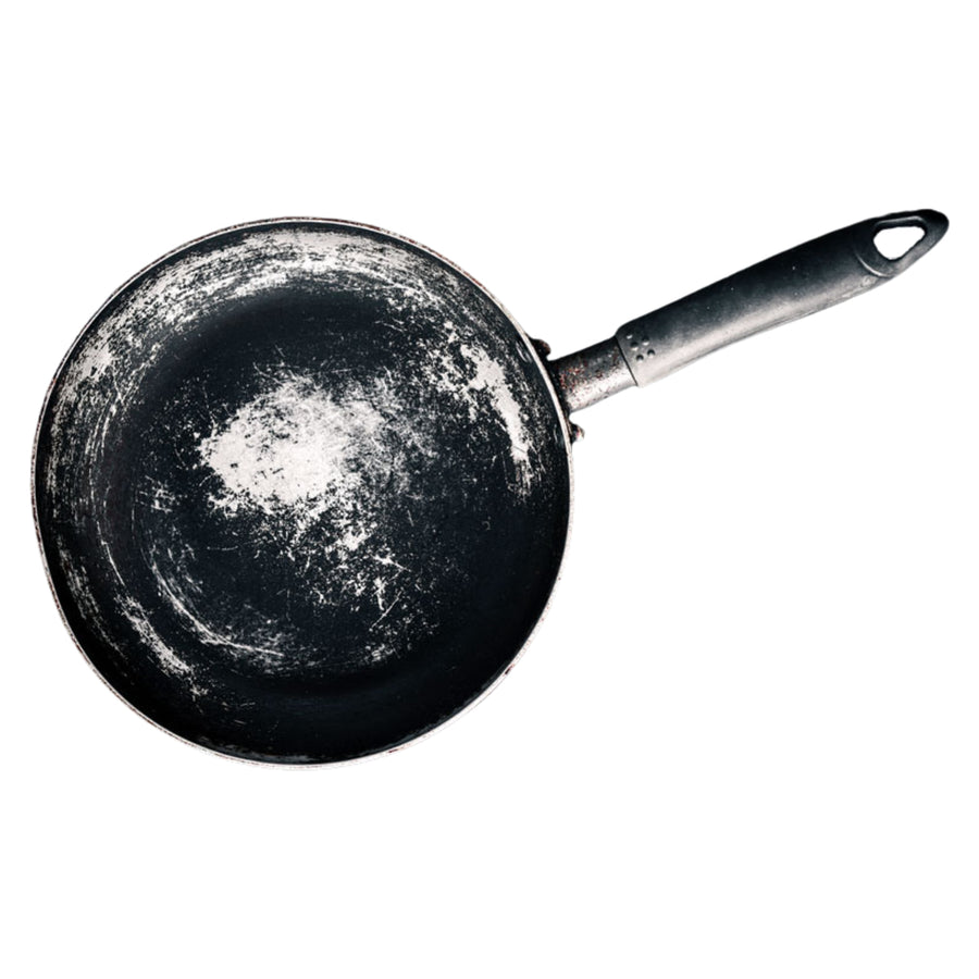 Old scratched Teflon nonstick frying pan with peeling coating