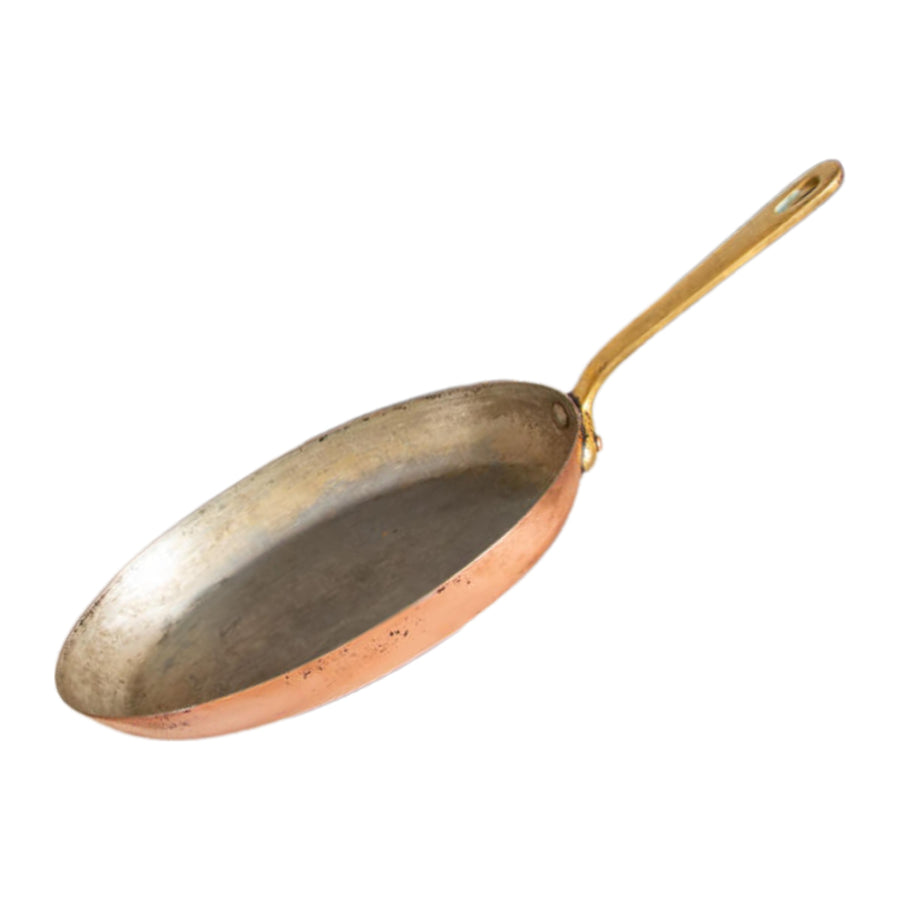 Old copper frying pan with a tarnished, worn lining