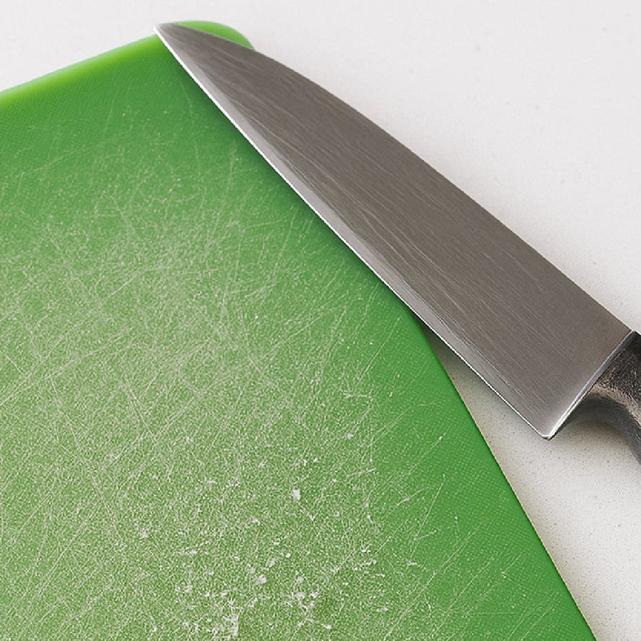 Scratched green plastic cutting board with a knife - knife grooves where bacteria and microplastics hide